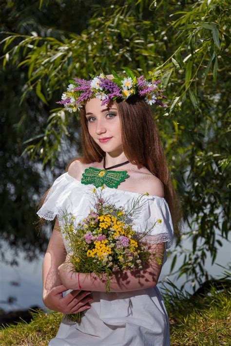 girl in white dress and wreath holding field flowers bouquet on green willow background 7th
