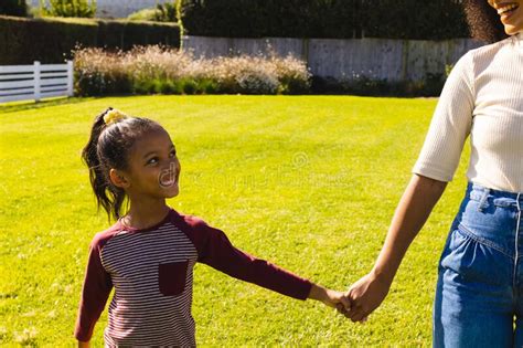 Midsection Of Biracial Mother Holding Happy Daughter S Hands While Standing On Field In Yard