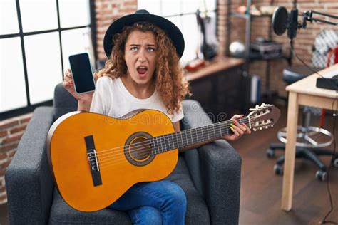 Young Caucasian Woman Playing Classic Guitar At Music Studio Holding