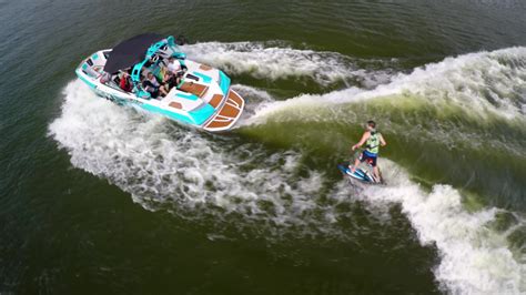 Aerial Shot Of A Man Wakeboard Wake Surfing Behind A Boat On A Lake