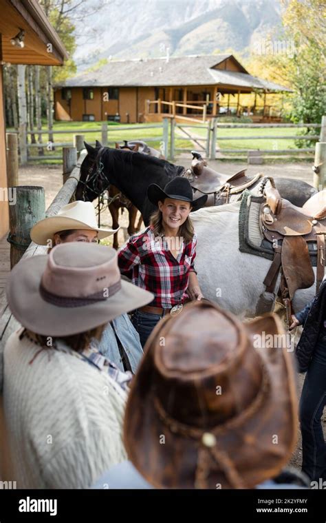 Rancher Helping Women Friends Prepare For Horseback Riding On Ranch