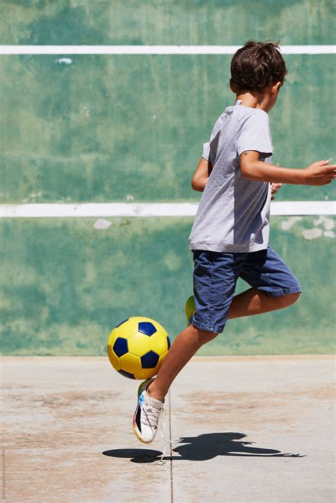 Unrecognizable Boy Playing Football On Asphalt By Guille Faingold