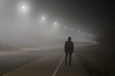 Young Man Alone Slowly Walking Under White Street Lights In Night Dark