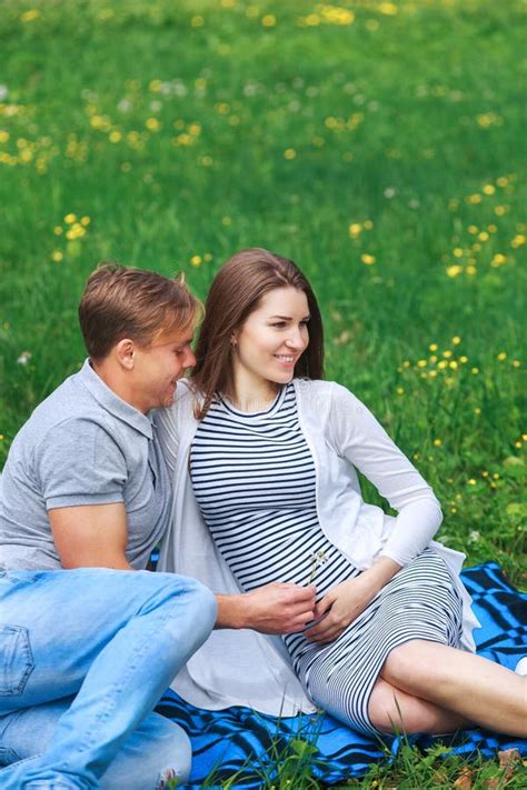 Happy Pregnant Woman With Her Husband Hugging And Smiling In Park Stock