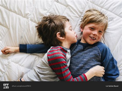 Little Boy Kissing His Brothers Cheek On A Bed Stock Photo Offset