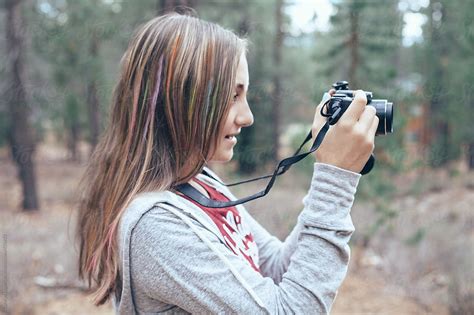 Teen Girl Taking Photos With Her Digital Camera In The Forest Del Colaborador De Stocksy