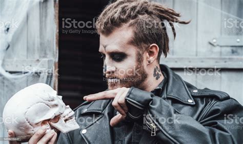 Scary Man With Dreadlocks Looking At Skull Celebrating Halloween