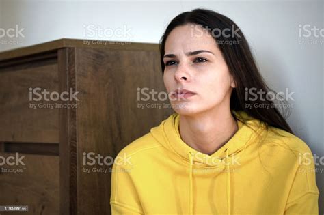 A Beautiful Young Woman Sitting And Looking Thoughtfully Into The