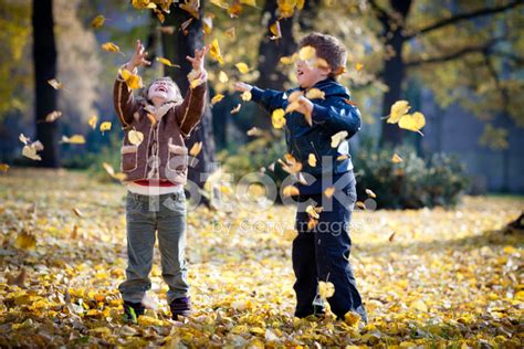 Children Playing With Leaves In Autumn Park Stock Photos