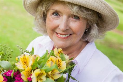 Premium Photo Close Up Of Smiling Mature Woman Holding Flowers At Park