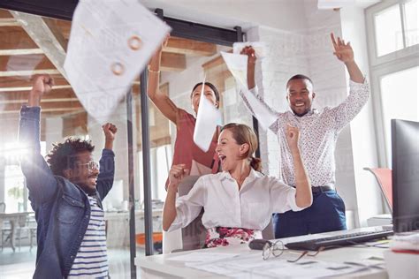 Exuberant business people celebrating, throwing paperwork overhead in office - Stock Photo ...