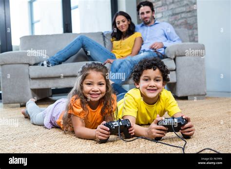 Children Playing Video Games On The Carpet In Living Room Stock Photo