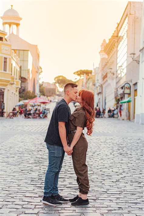 giovani coppie romantiche che baciano sulla strada della città al tramonto · foto gratuita