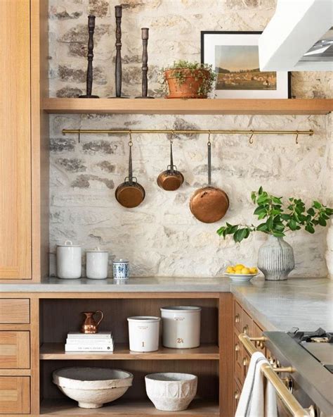 A Kitchen With Pots And Pans Hanging On The Wall Next To An Open Shelf