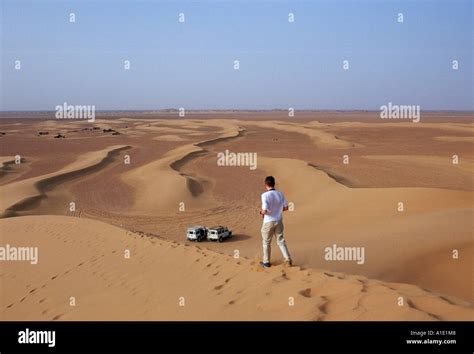 Young Man Walks Down The Sand Dunes In The Sahara Desert Morocco Stock