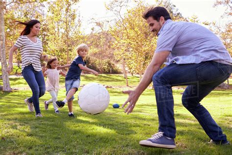 Family playing soccer in park together - Stock Photo - Dissolve