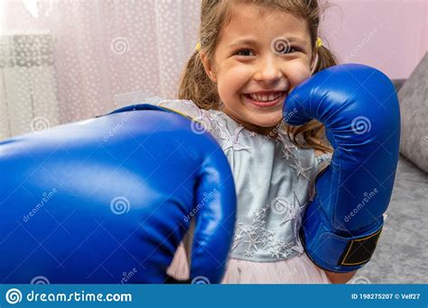 Little Girl Wearing Blue Boxing Gloves And A Holiday Dress With Stars