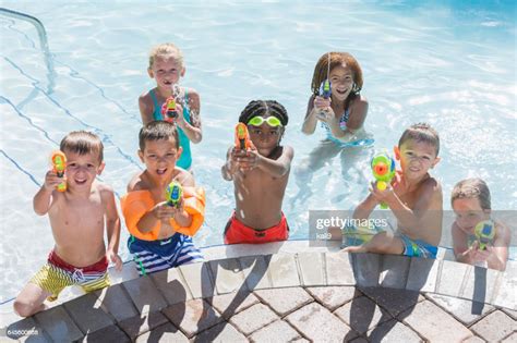 Groupe Multiethnique Denfants Dans La Piscine Avec Des Fusils Squirt