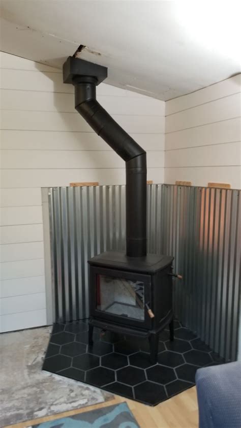 A Black Stove Sitting Inside Of A Living Room Next To A Metal Wall