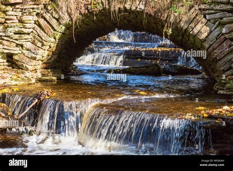 Waterfall Under An Old Arch Bridge Stock Photo Alamy