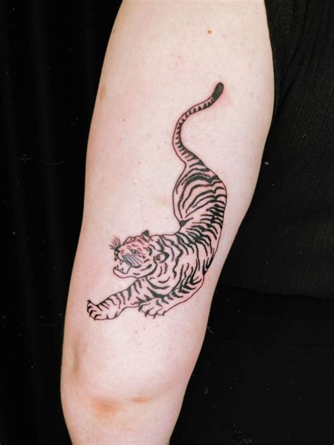 A Woman S Arm With A Tattoo Of A Tiger On The Back Of It