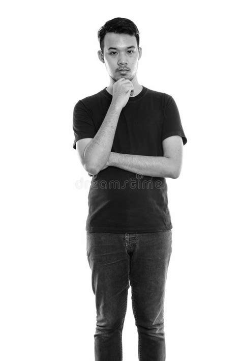 Studio Shot Of Young Asian Man Standing While Thinking Stock Image