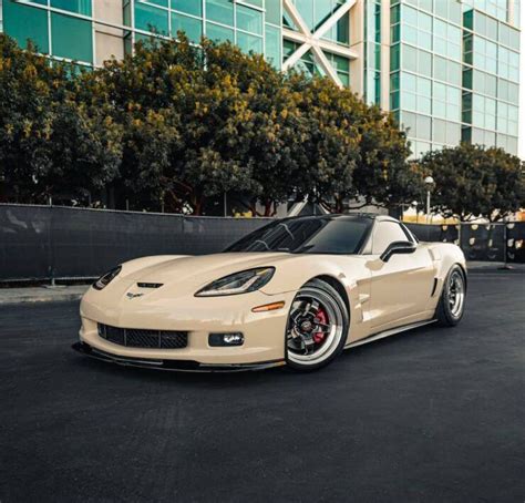 A White Sports Car Parked In Front Of A Tall Building