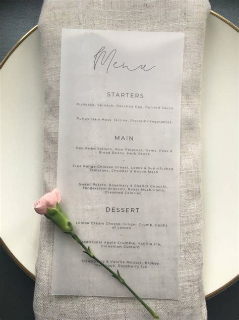 A Table Setting With A Menu And A Single Rose On The Place Card For An