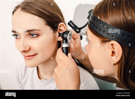 Doctor Examining Ear Woman Patient Using An Otoscope In A Doctors