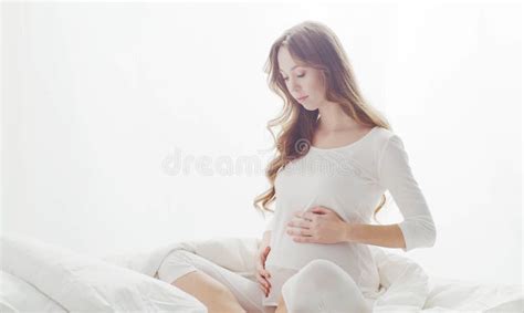 happy pregnant woman touching her beautiful belly sitting in the bed pregnancy motherhood and