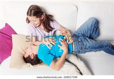 Junge Mädchen Kitzelt Ihren Jüngeren Bruder Stockfoto 268017188
