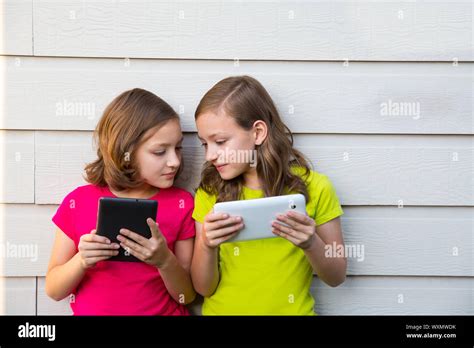 Twin Sister Girls Playing With Tablet Pc Happy On White Wall Looking