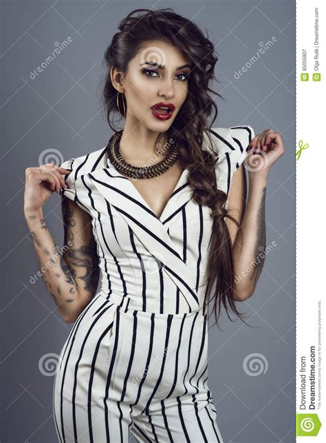 Portrait Of Young Gorgeous Dark Haired Tattooed Lady In Striped Overall And Splendid Necklace