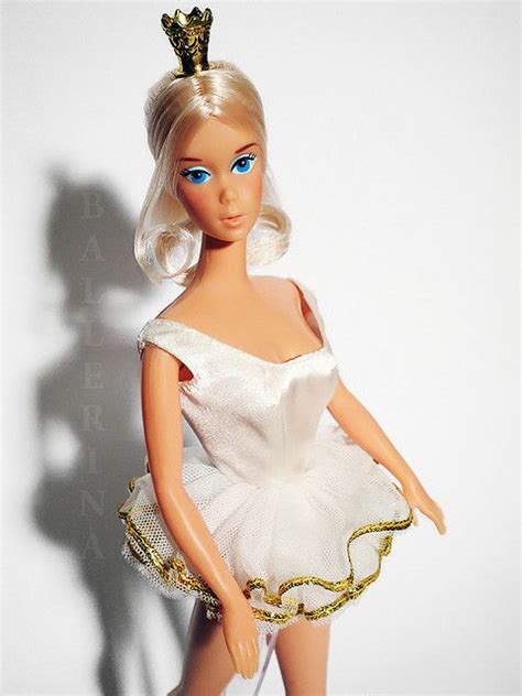 A Barbie Doll Wearing A White Dress And Gold Tiara Standing In Front