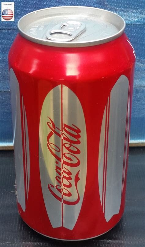 A Can Of Coca Cola Sitting On Top Of A Table Next To A Blue Wall