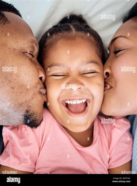 Top View Mother And Father Kiss Girl On Cheeks Bonding And Loving In