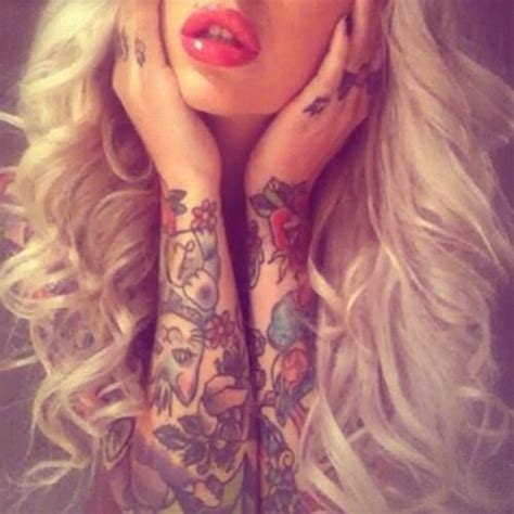 a woman with long blonde hair and tattoos on her arms is posing for the camera