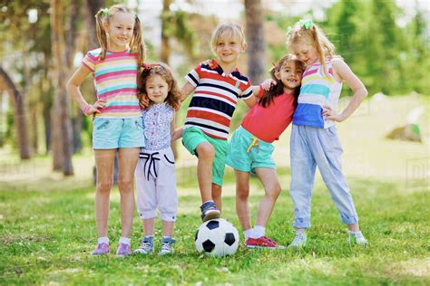Group Of Little Friends Playing Football In The Park Stock Photo