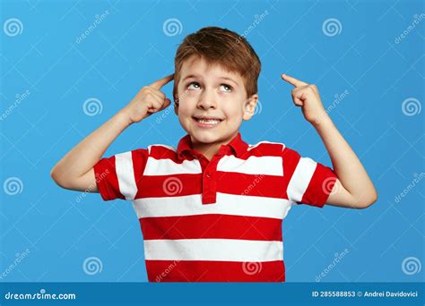 Thoughtful Preschool Boy In Red Striped Polo Shirt Pointing At Head And