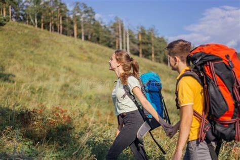 Couple Of Tourists With Backpacks Hiking Up A Mountain Stock Photo