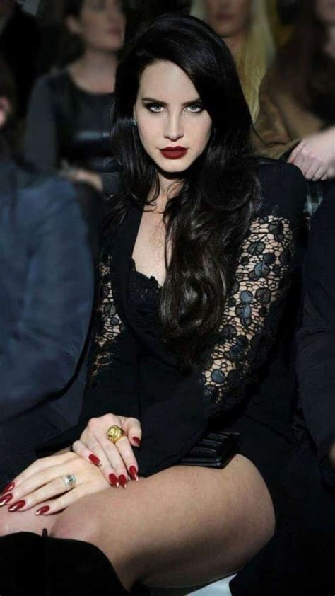 A Woman With Long Black Hair And Red Nails Sitting In Front Of A Group Of People