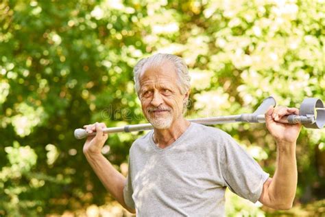 Vital Senior With Walking Stick In The Garden In Rehab Stock Photo
