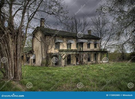Old Abandoned Farmhouse In The Midwest Surrounded By Leafless Trees And