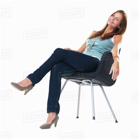 Studio Shot Of Young Woman Sitting On Chair And Smiling Stock Photo