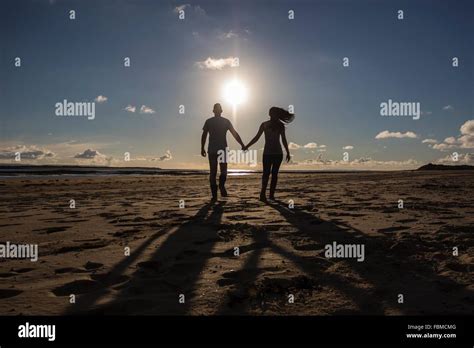 Silueta De Una Pareja Caminando Por La Playa Cogidos De La Mano