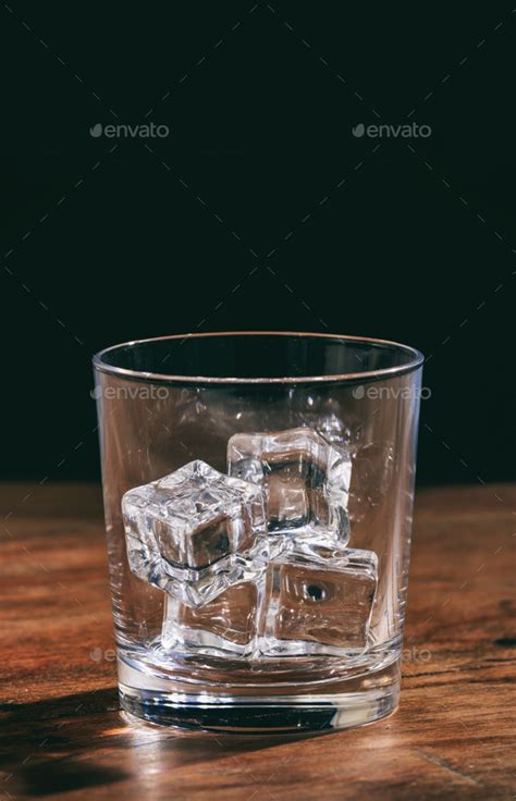 Crystal Whiskey Glass With Ice Cubes On A Wooden Table Stock Photo By