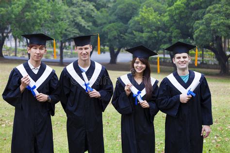 Students In Graduation Gowns Showing Diplomas With Thumbs Stock Image