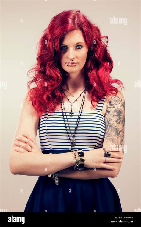 Young Woman With Red Hair And Tattoos In Striped Dress Looking Into The
