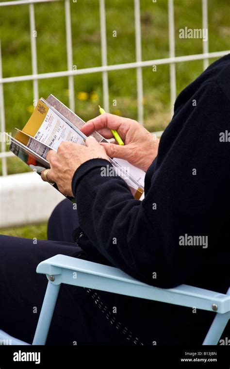 Closeup Of A Spectator Seated Looking Through A Program Bookletplacing