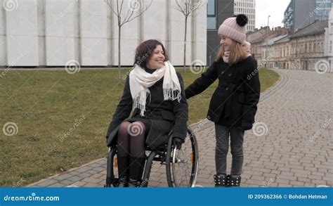 little daughter walking with her handicapped mother in a city stock footage video of pushing
